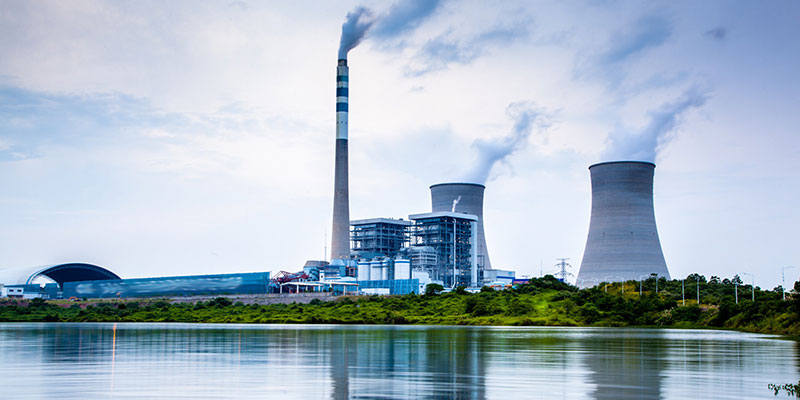 Central térmica con chimenea y torres de refrigeración junto a un embalse (sector industrial)