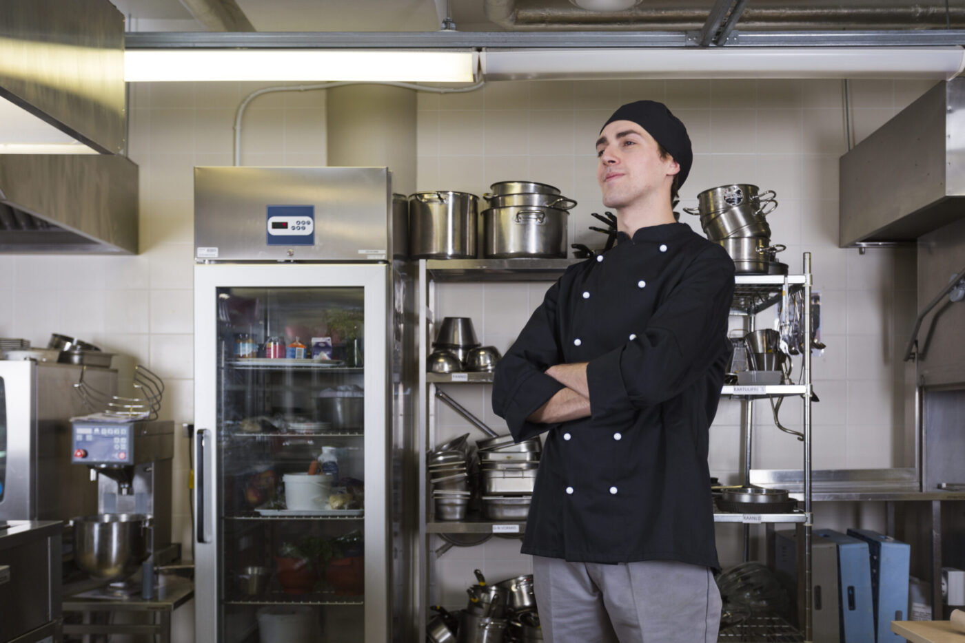 Cocinero con uniforme negro y gorro en cocina industrial, formación para el empleo