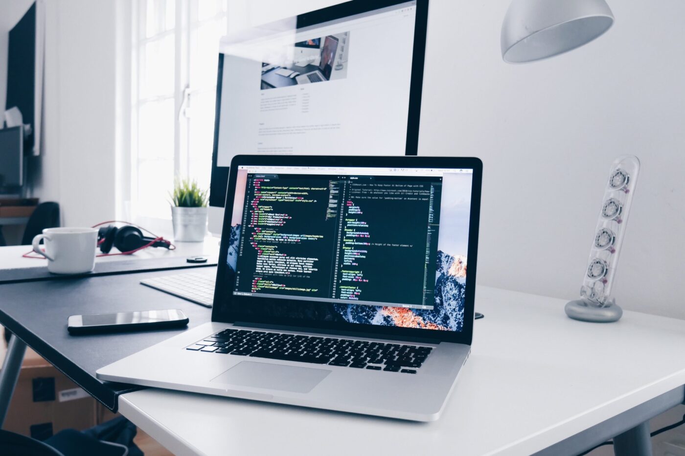 Portátil con editor de código en pantalla sobre escritorio, cursos online