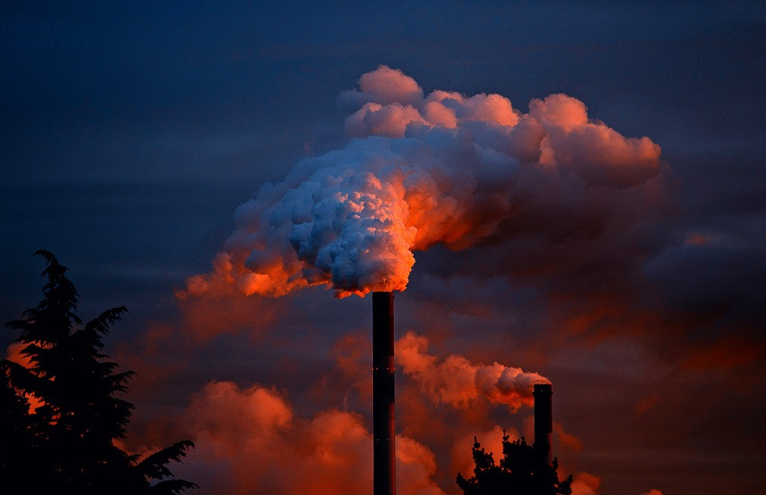 Chimenea industrial emitiendo humo espeso al atardecer, cursos sector industrial