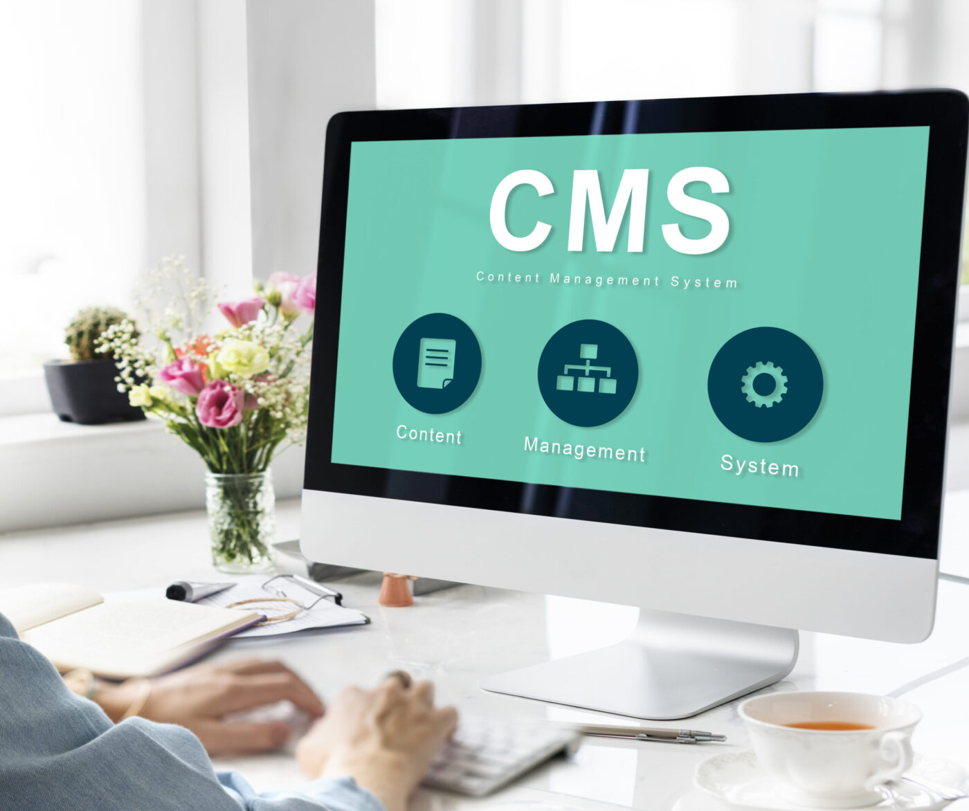 Monitor con interfaz 'CMS' en un escritorio y manos tecleando, cursos online