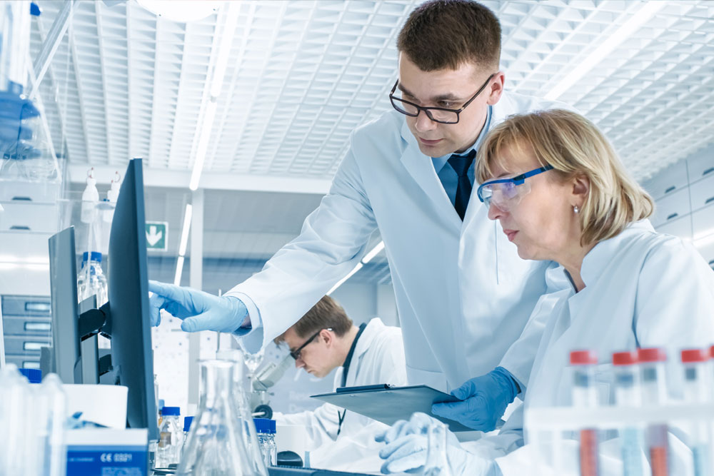 Técnicos de laboratorio revisando resultados en un monitor — formación para el empleo