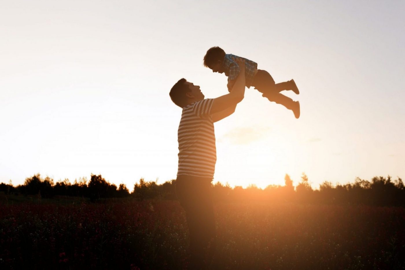 Padre levantando a su hijo al atardecer, escena familiar — formación para el empleo