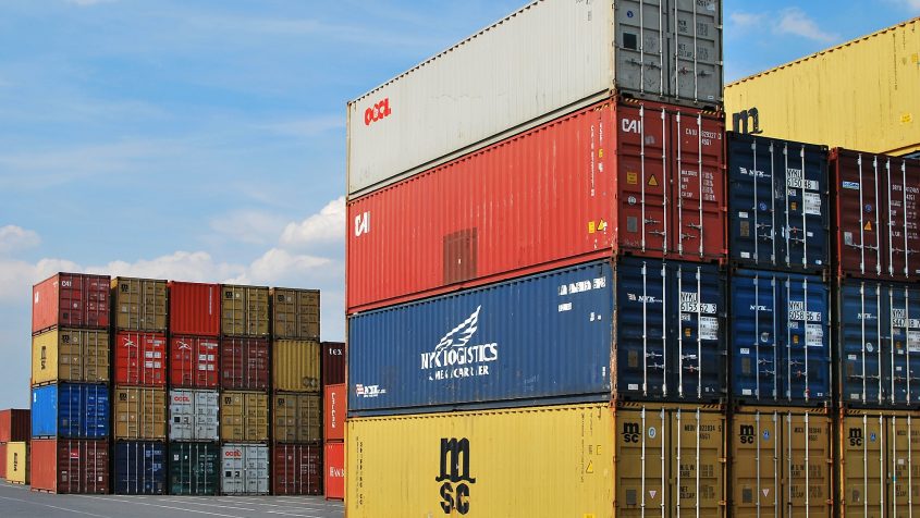 Contenedores marítimos apilados en un muelle con logotipos visibles — cursos sector industrial