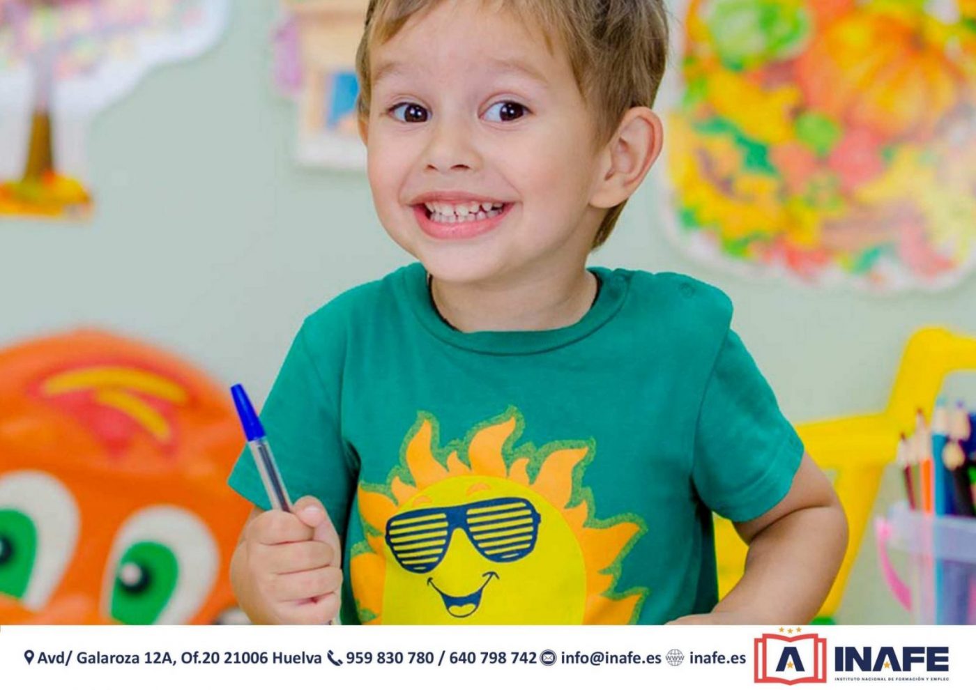 Niño sonriente en aula con bolígrafo, cursos en Huelva