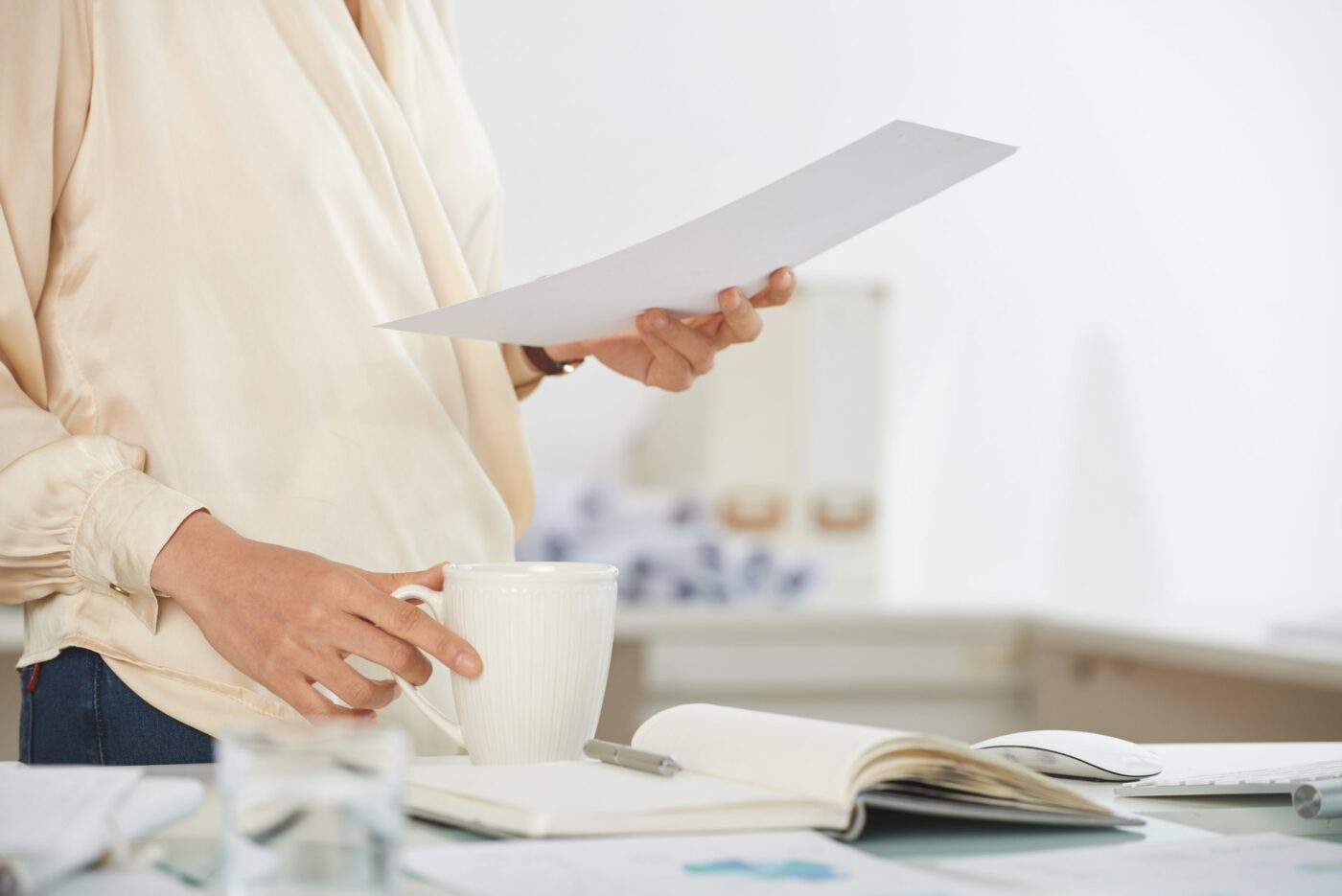 Mujer sosteniendo documento y taza blanca en un escritorio — formación para el empleo