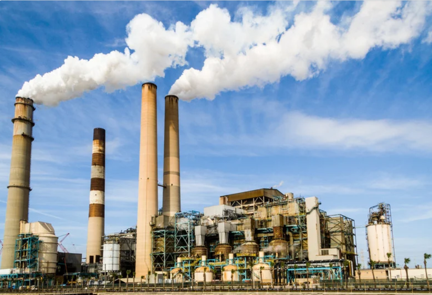 Planta industrial con varias chimeneas altas que emiten vapor blanco