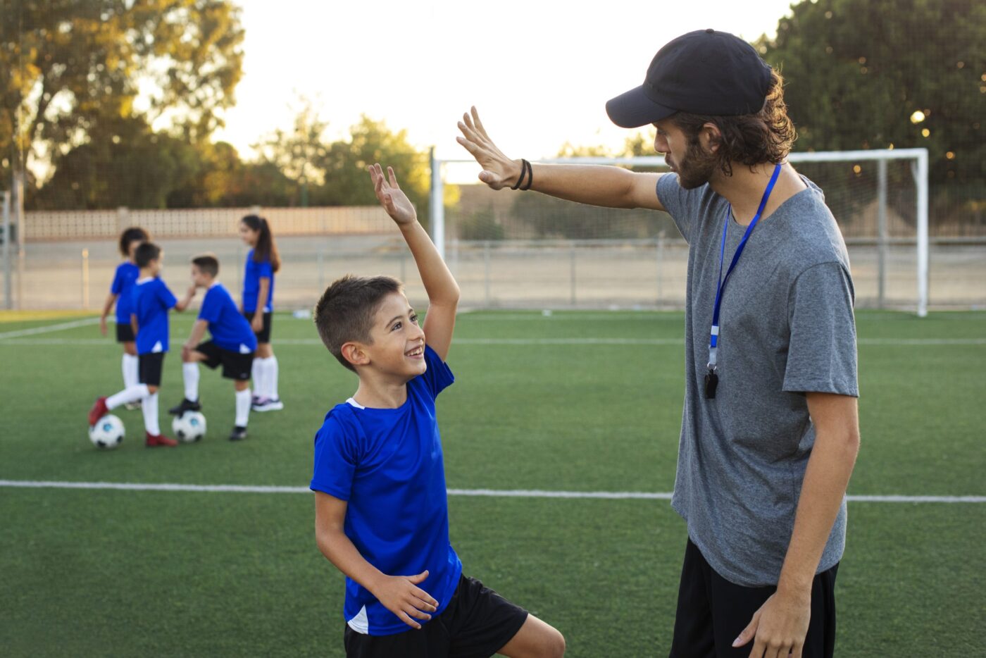 Entrenador de fútbol felicitando a un niño en el campo de entrenamiento — formación para asociaciones