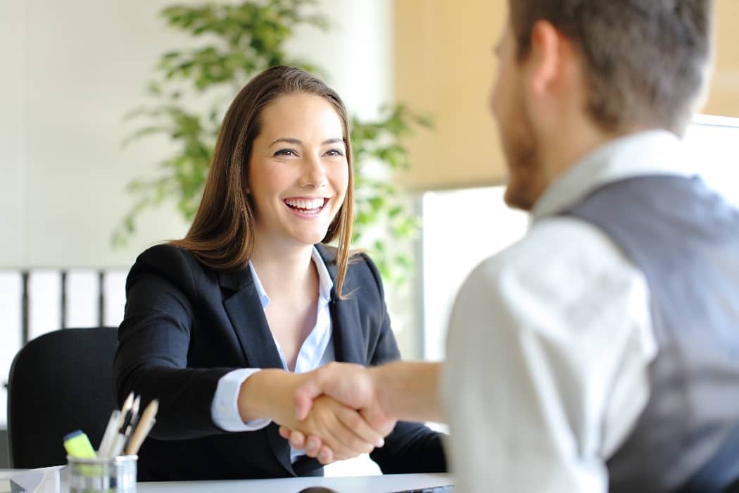 Mujer sonriente estrechando la mano en entrevista de trabajo, formación para el empleo