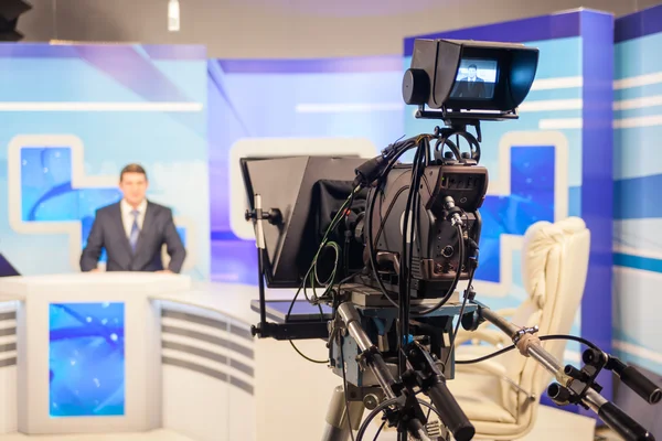 Cámara de estudio de televisión enfocando a presentador en plató de noticias, cursos online