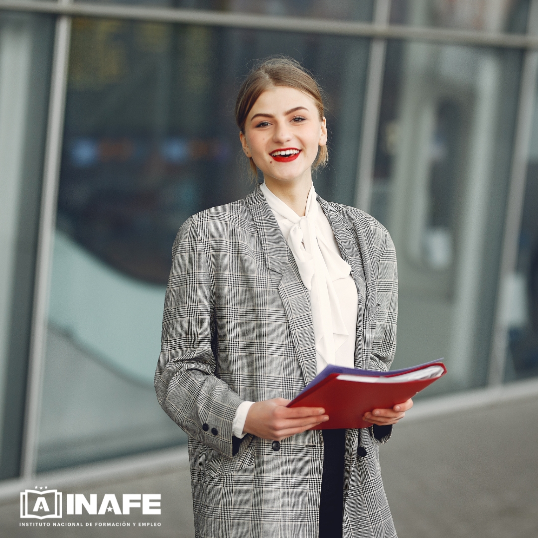 Mujer sonriente con carpeta roja delante de un edificio moderno, formación para el empleo