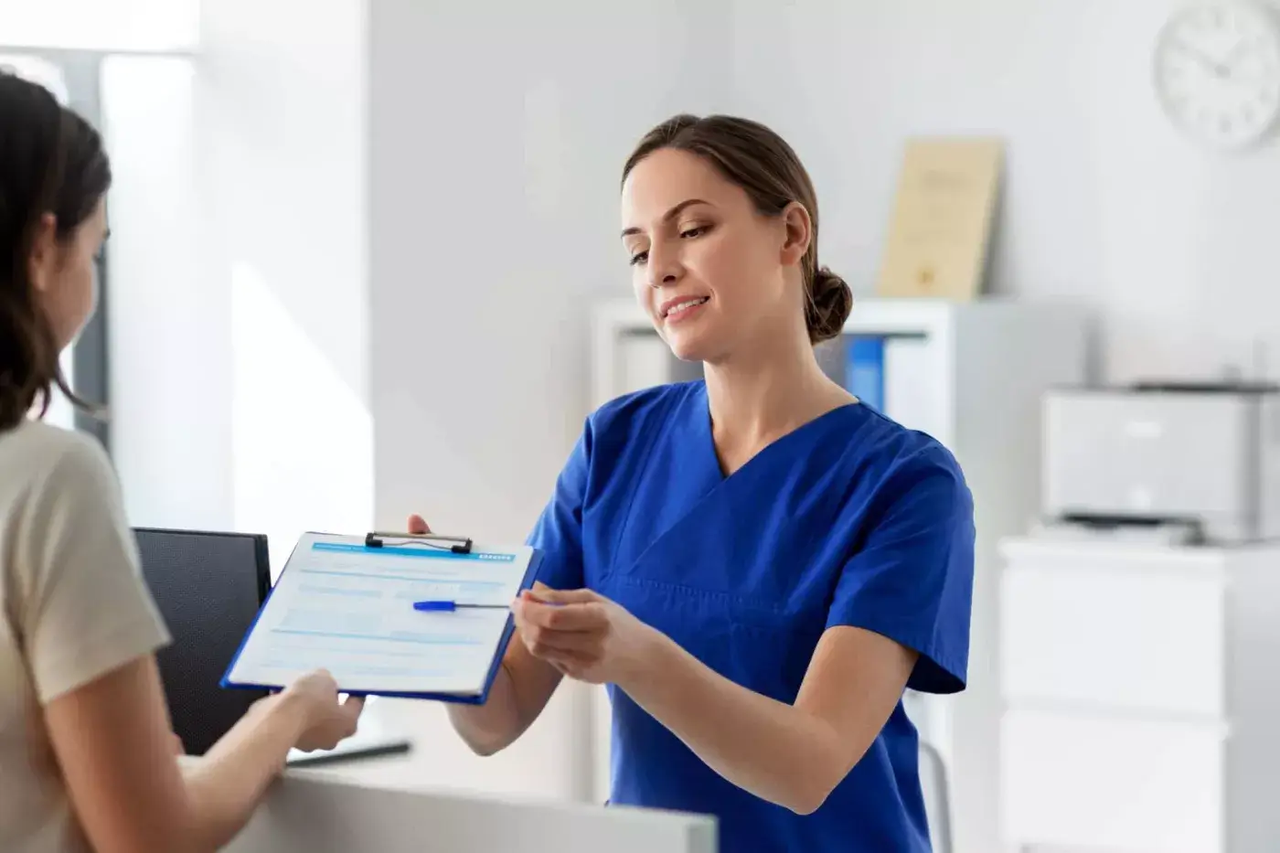 Recepcionista sanitaria entregando un portapapeles con formulario — formación para el empleo