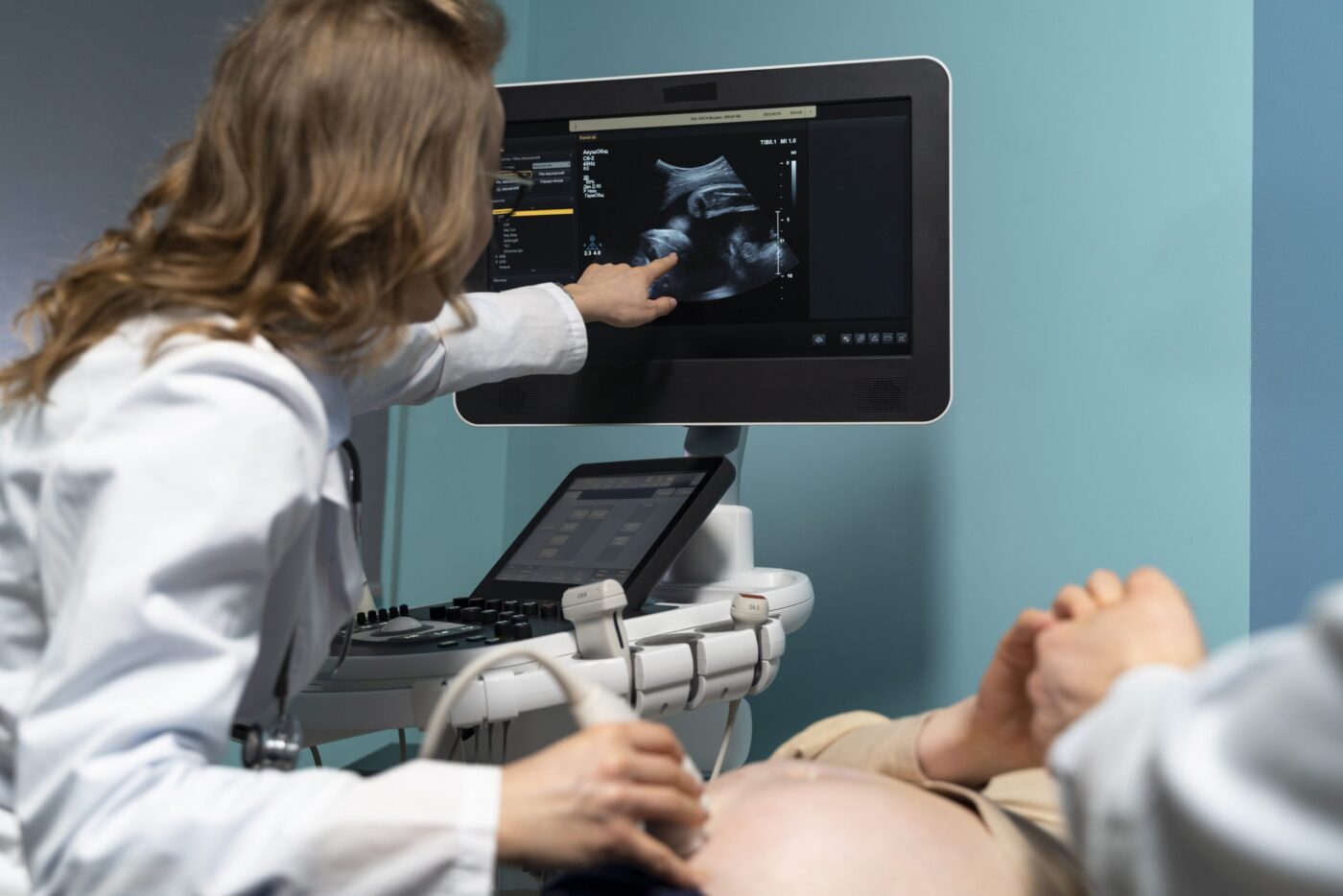 Ginecóloga señalando ecografía fetal en monitor — formación para el empleo