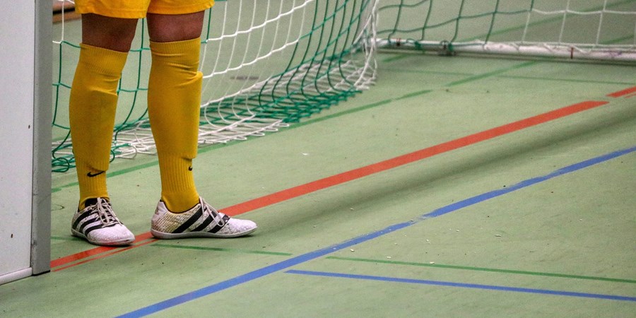 Portero de fútbol sala de pie junto a la portería, formación para el empleo