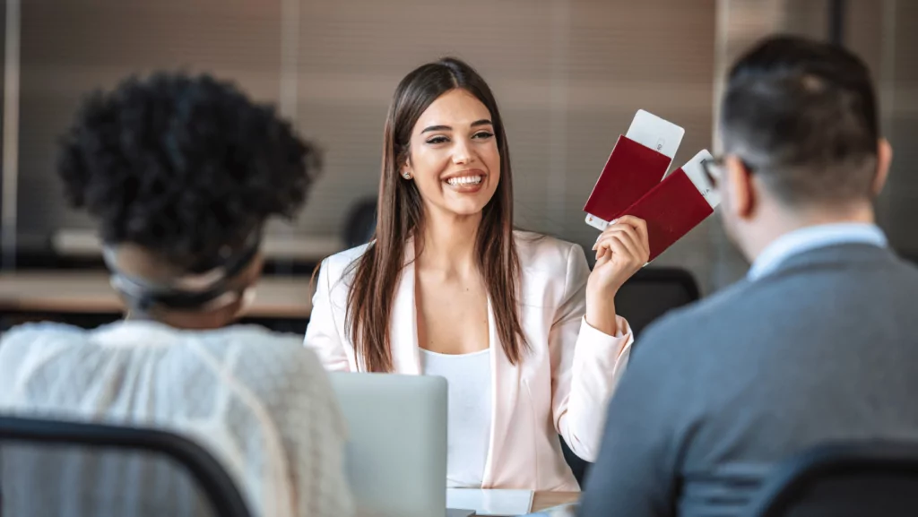 Mujer sonriente mostrando dos pasaportes a dos personas (formación para el empleo)