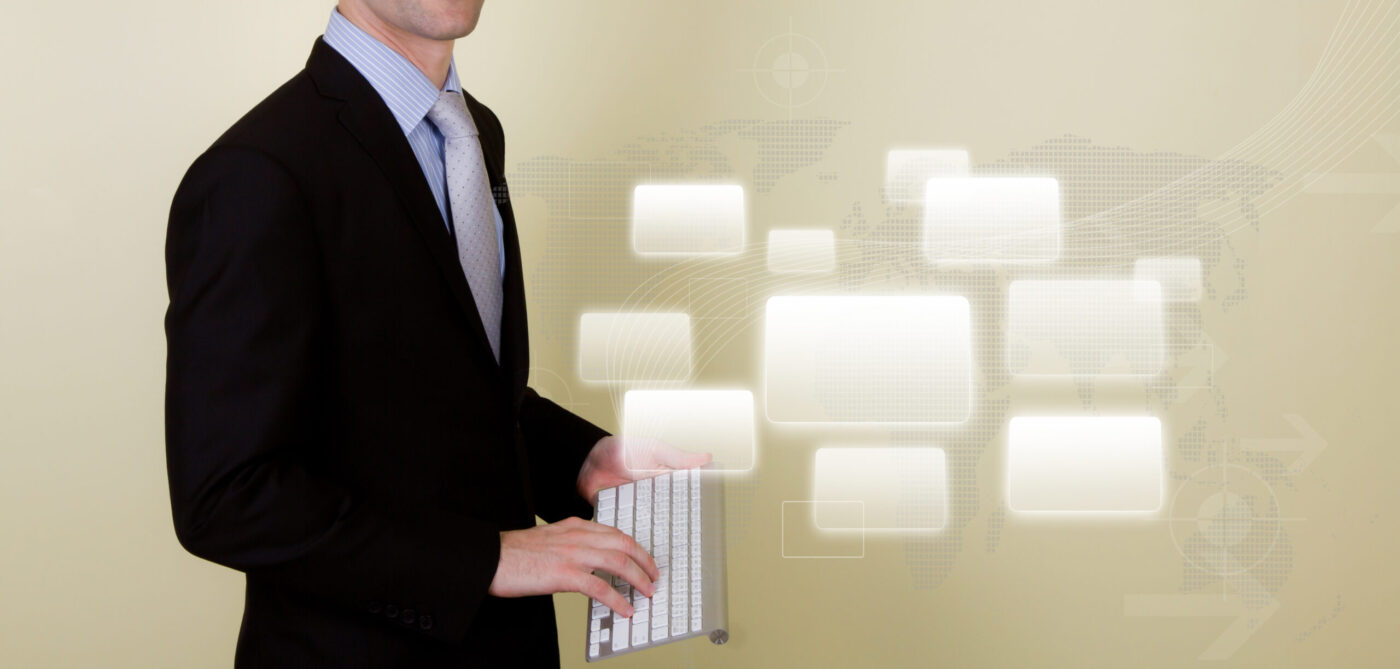 Hombre de traje sosteniendo un teclado inalámbrico frente a iconos digitales — cursos online