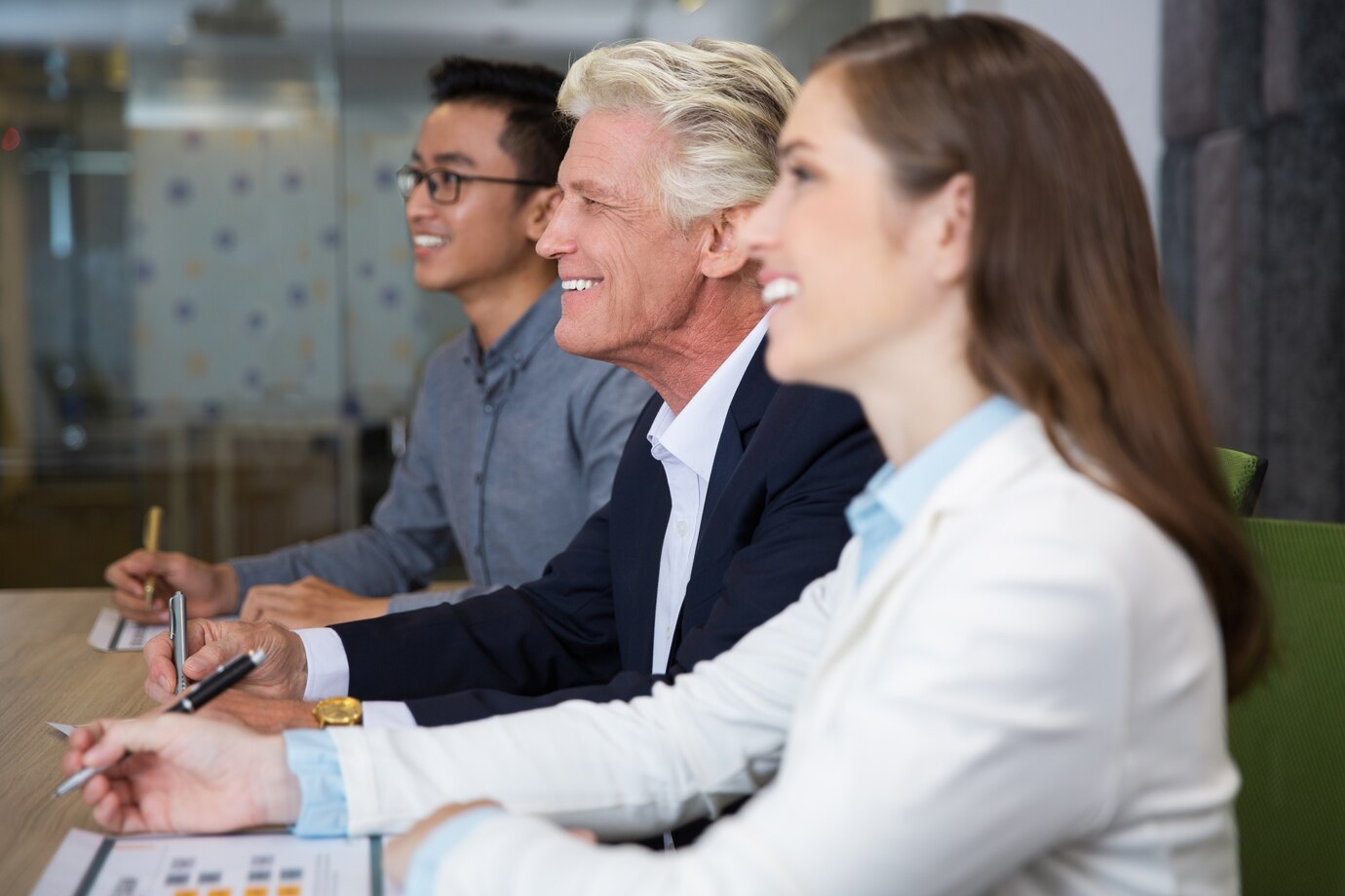Tres profesionales sonriendo y tomando notas en una sesión de formación para el empleo