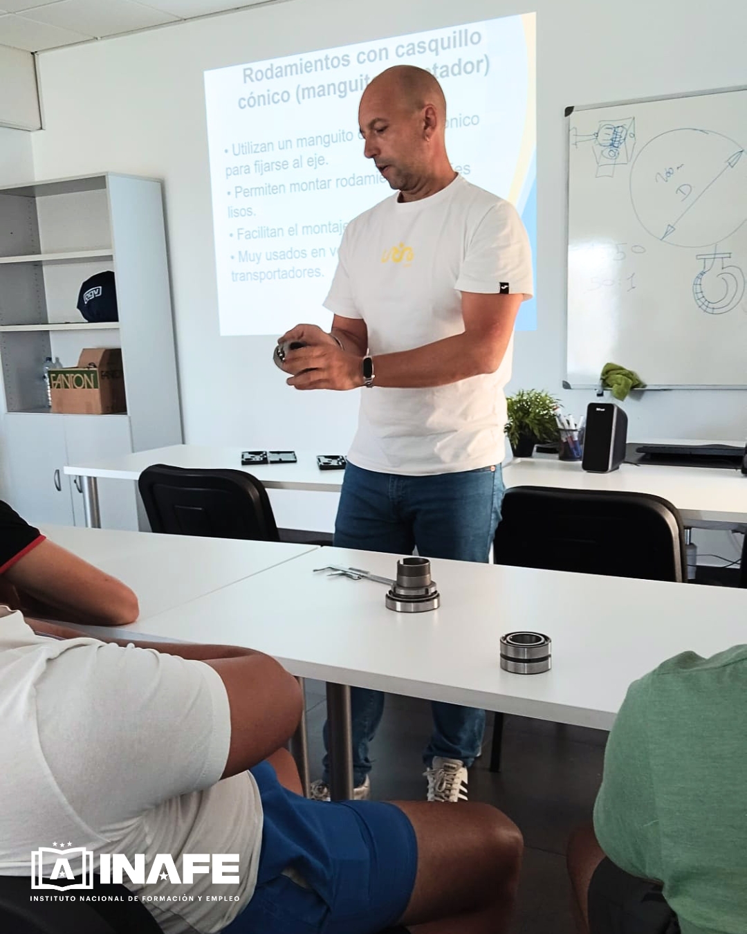 Instructor mostrando un rodamiento en clase de mecánico industrial