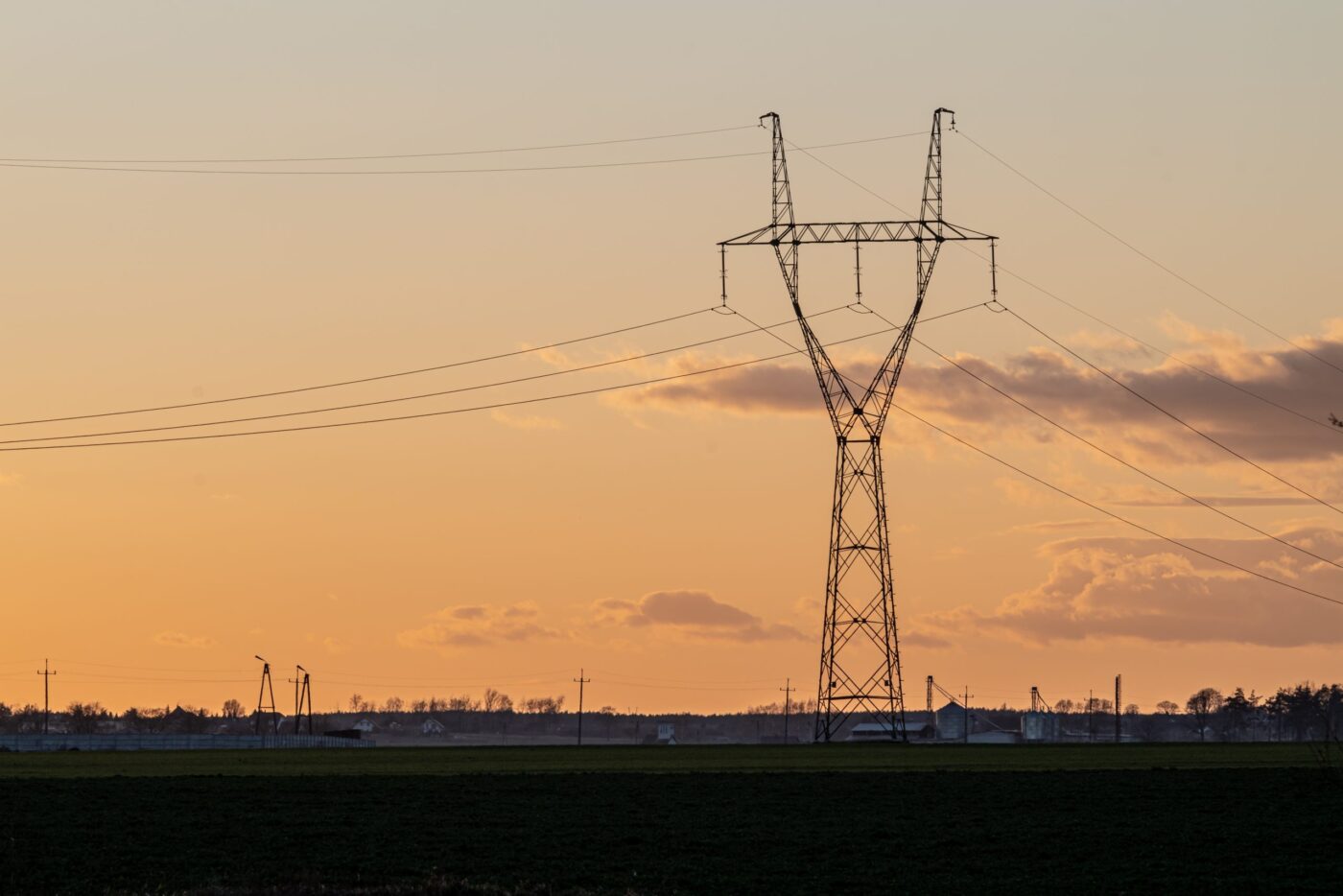 Torre eléctrica de alta tensión en campo al atardecer — cursos sector industrial