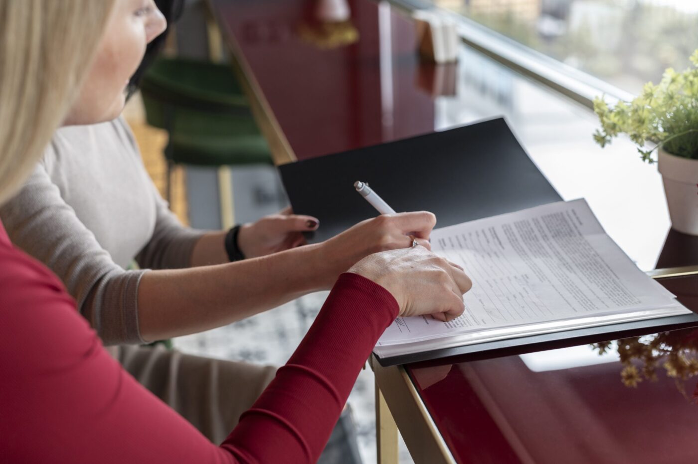Manos firmando un formulario en carpeta negra sobre una mesa — formación para el empleo