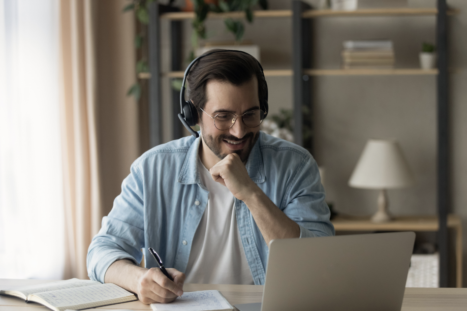 Hombre con auriculares y portátil tomando notas en cursos online