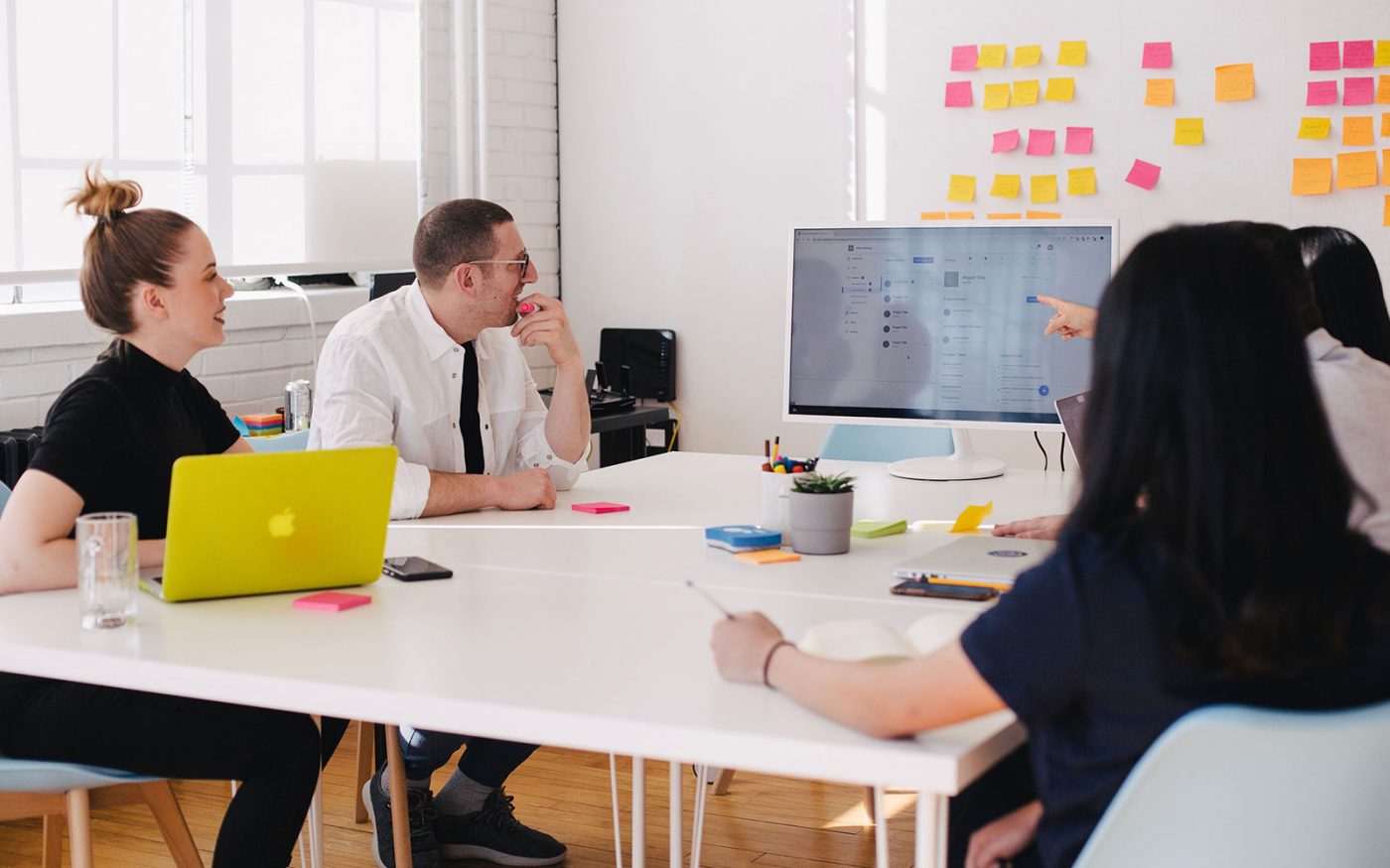 Equipo reunido alrededor de una mesa mirando una pantalla con interfaz web, cursos online