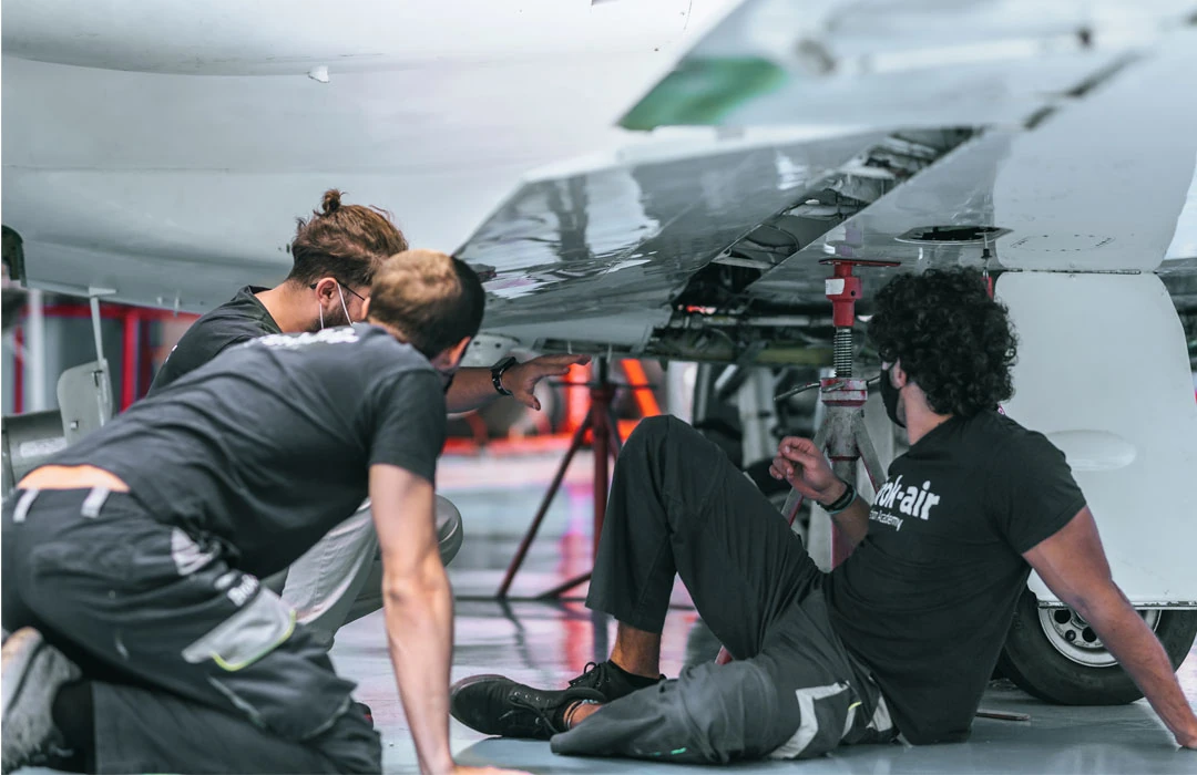 Técnicos inspeccionando el ala de un avión, mantenimiento industrial