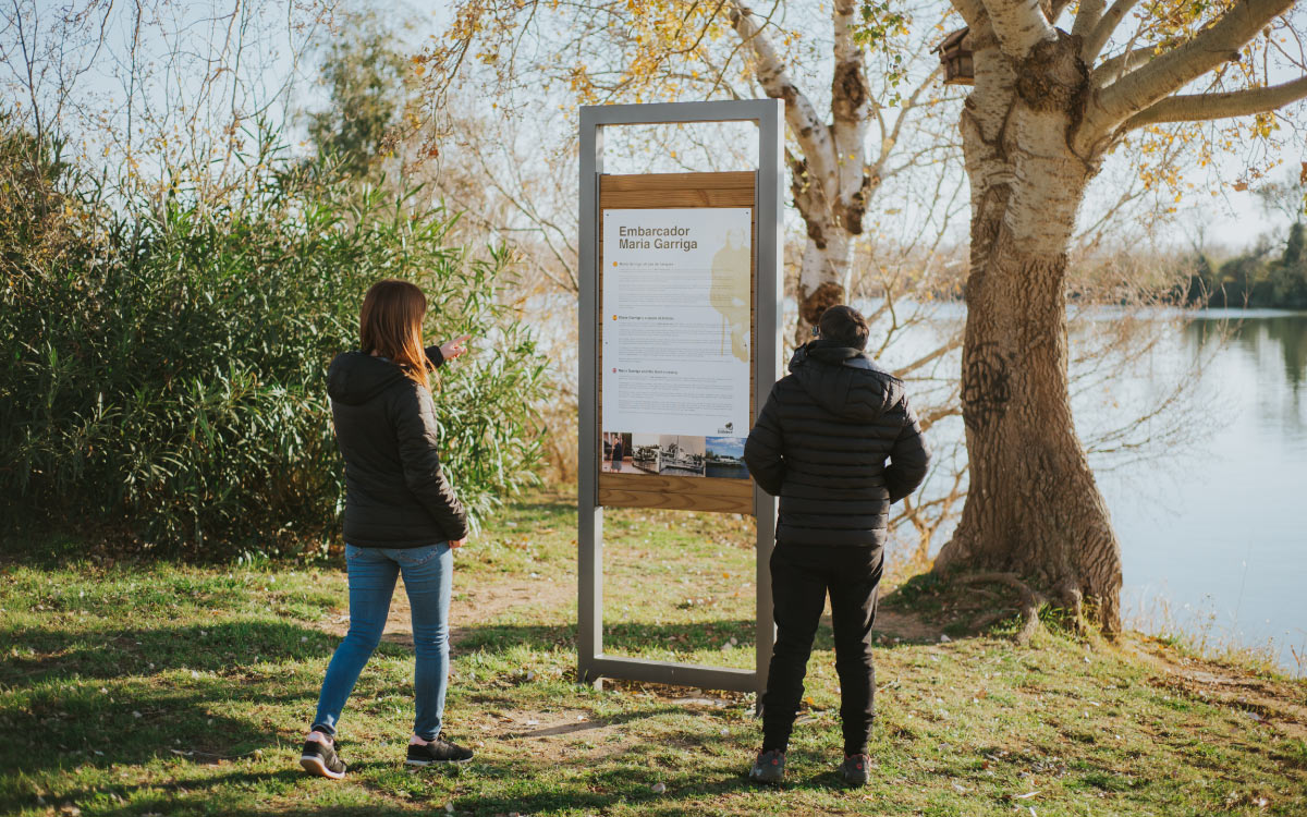 Dos personas leyendo un panel informativo junto al río (formación para ayuntamientos)
