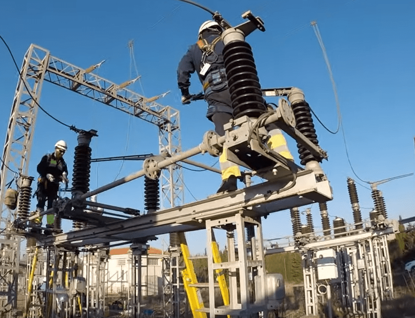 Operarios con EPI realizando mantenimiento industrial en la estructura de una subestación eléctrica.