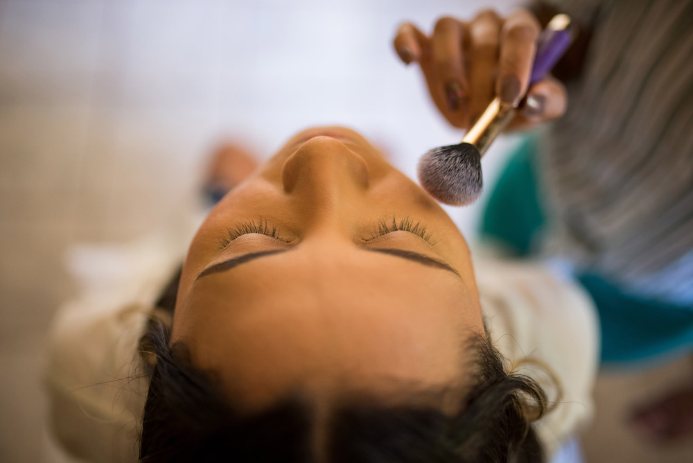 Rostro de mujer con ojos cerrados mientras le aplican maquillaje con brocha, cursos gratuitos