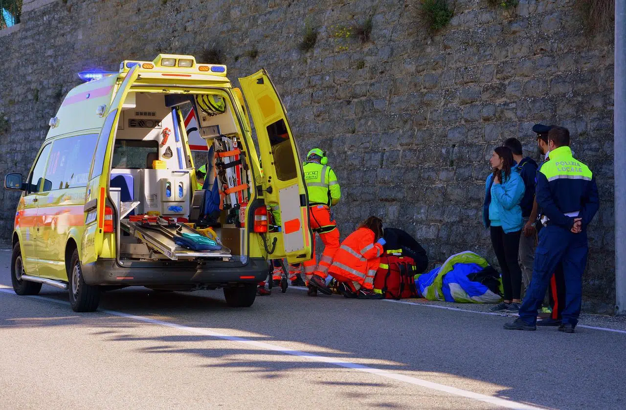 Paramédicos atendiendo a una persona junto a una ambulancia abierta — formación para administraciones públicas