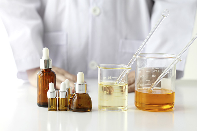 Frascos gotero y vasos de precipitados con líquidos amarillos en laboratorio — cursos sector industrial