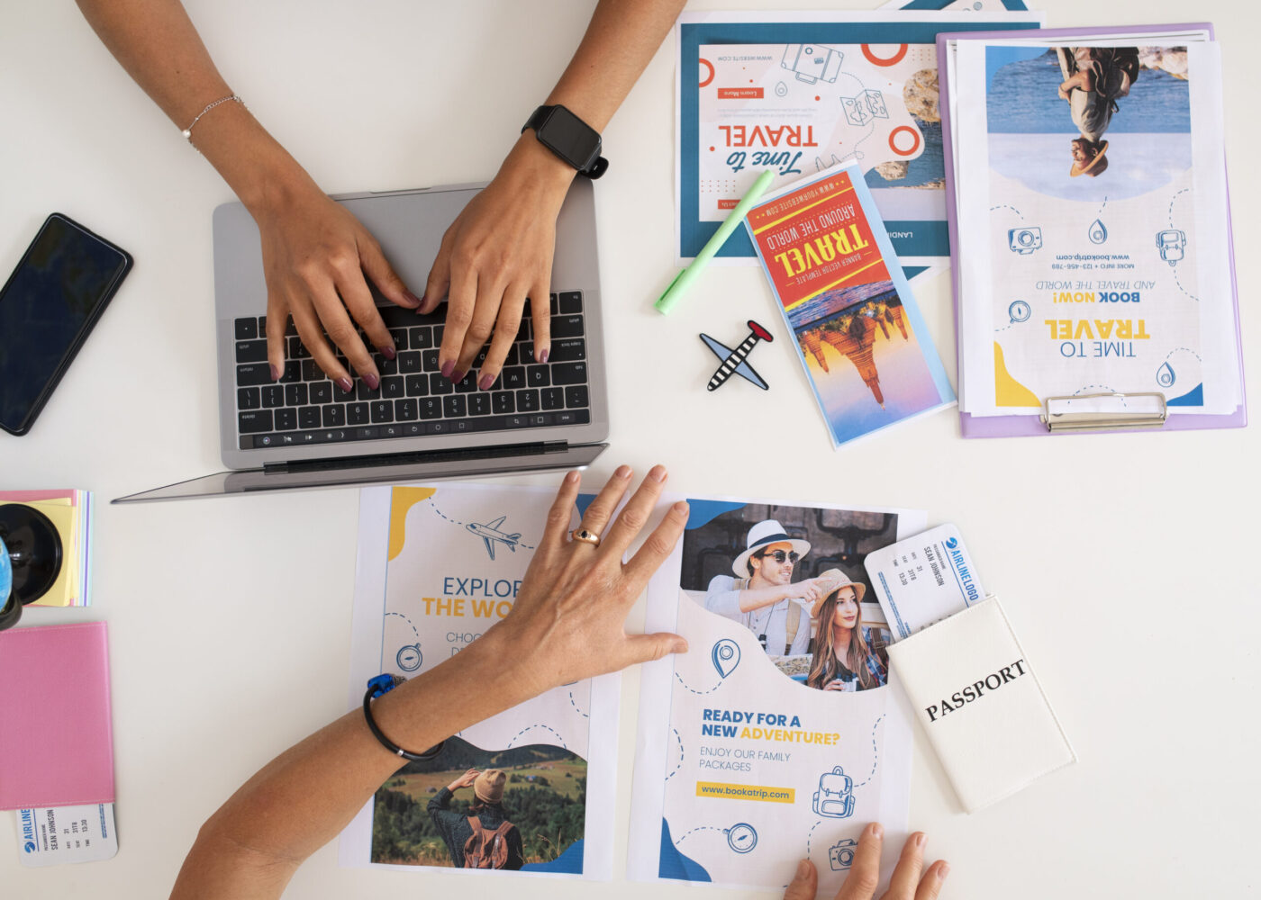 Manos sobre un portátil junto a folletos de viaje, pasaporte y billete — cursos online