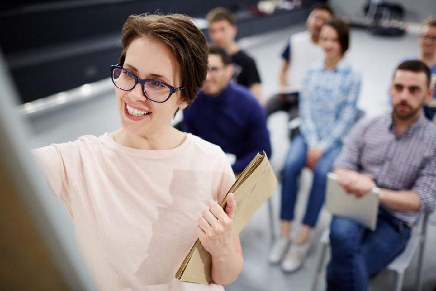 Formadora sonriente señalando un tablero, sesión de formación para el empleo