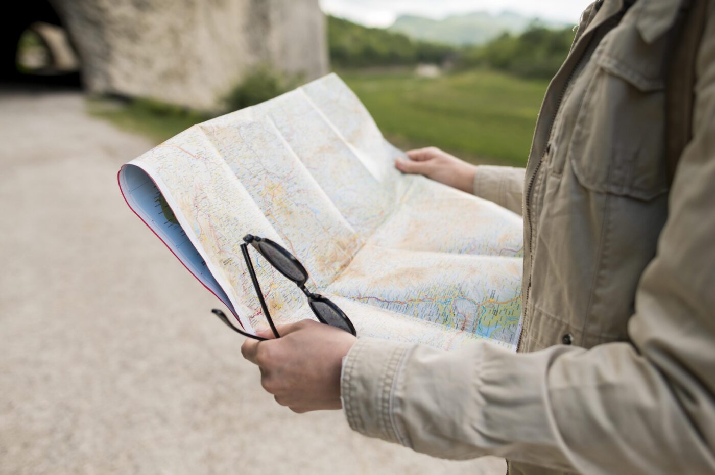 Manos sosteniendo un mapa abierto y unas gafas de sol, cursos en Huelva