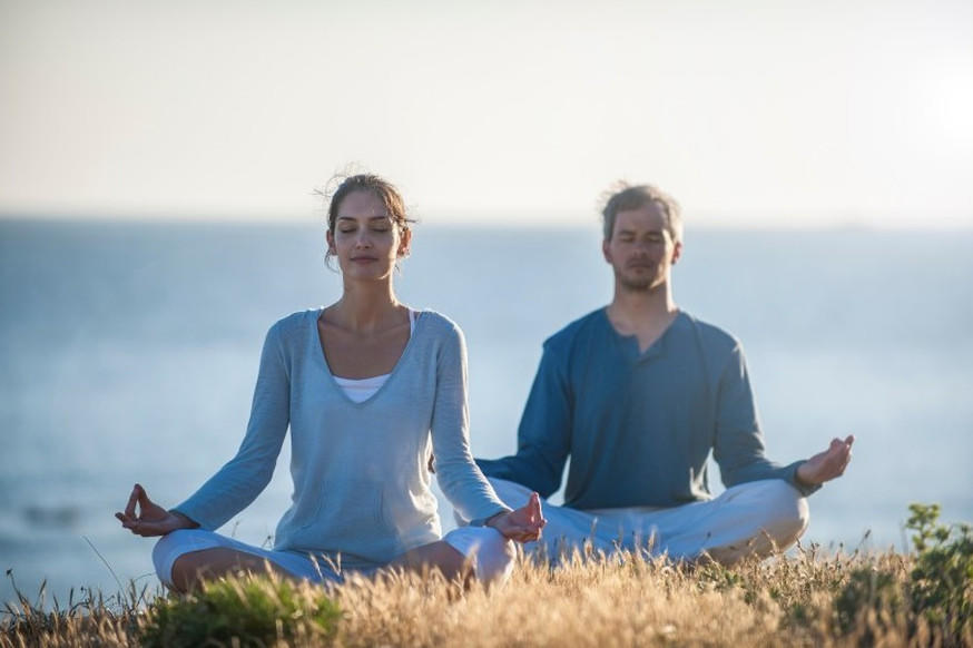 Pareja meditando sentada frente al mar, cursos online