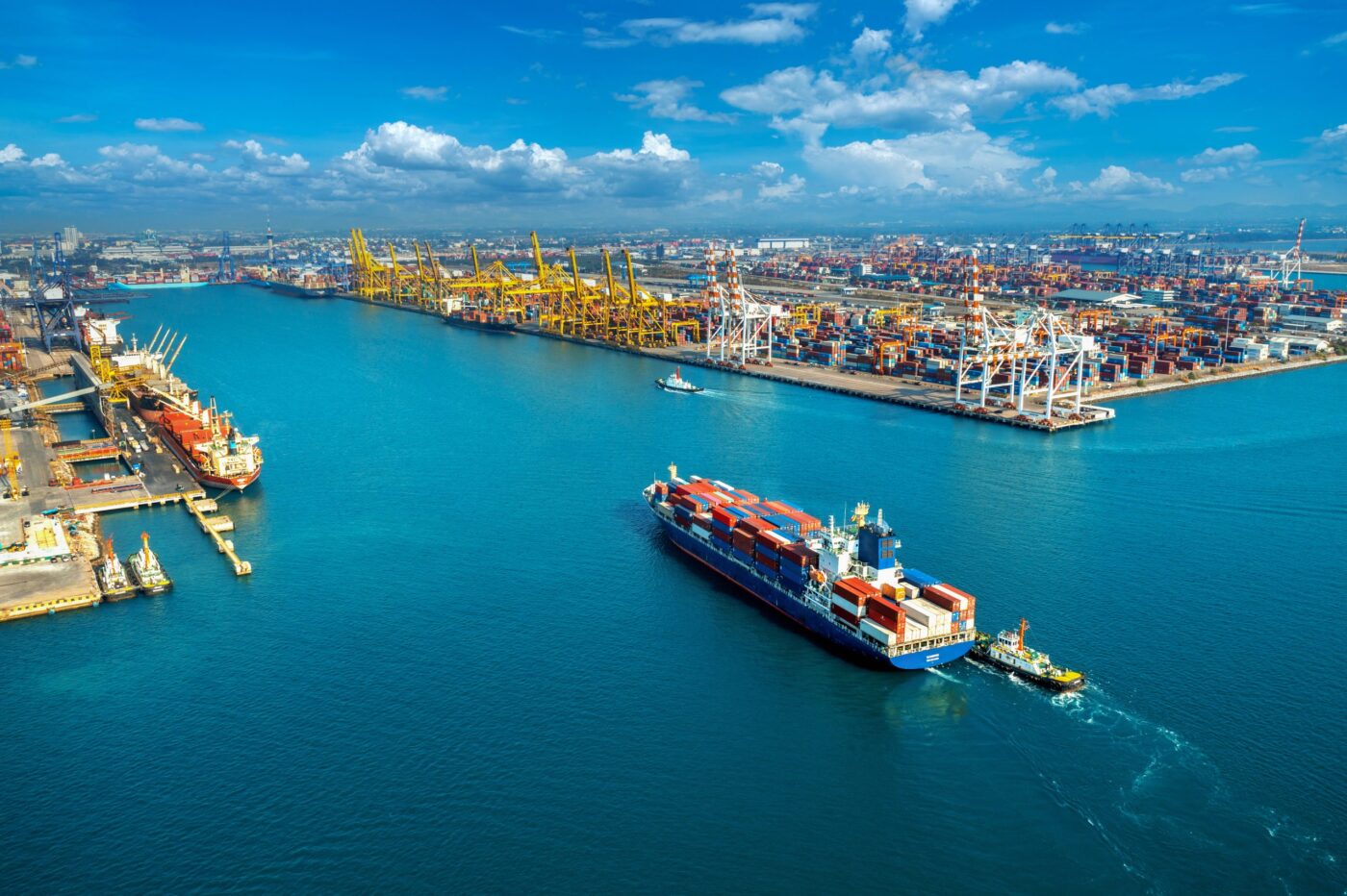 Buque portacontenedores remolcado en el puerto junto a grúas y pilas de contenedores — cursos de maquinaria
