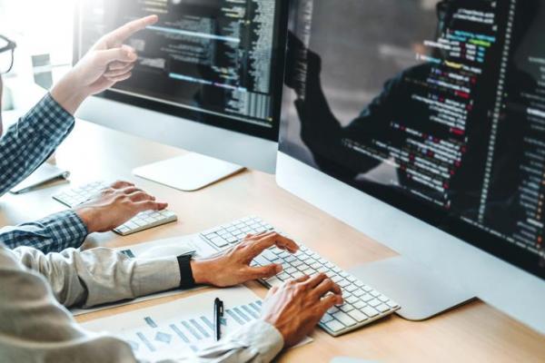Programadores revisando código en monitores, cursos online